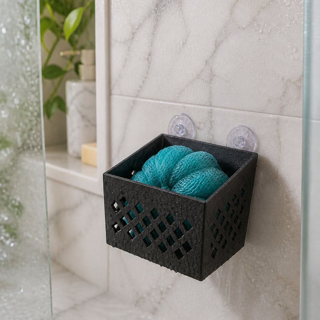 Black ventilated Loofah Pod inner basket mounted on a shower wall holding a teal loofah — digital visualization.